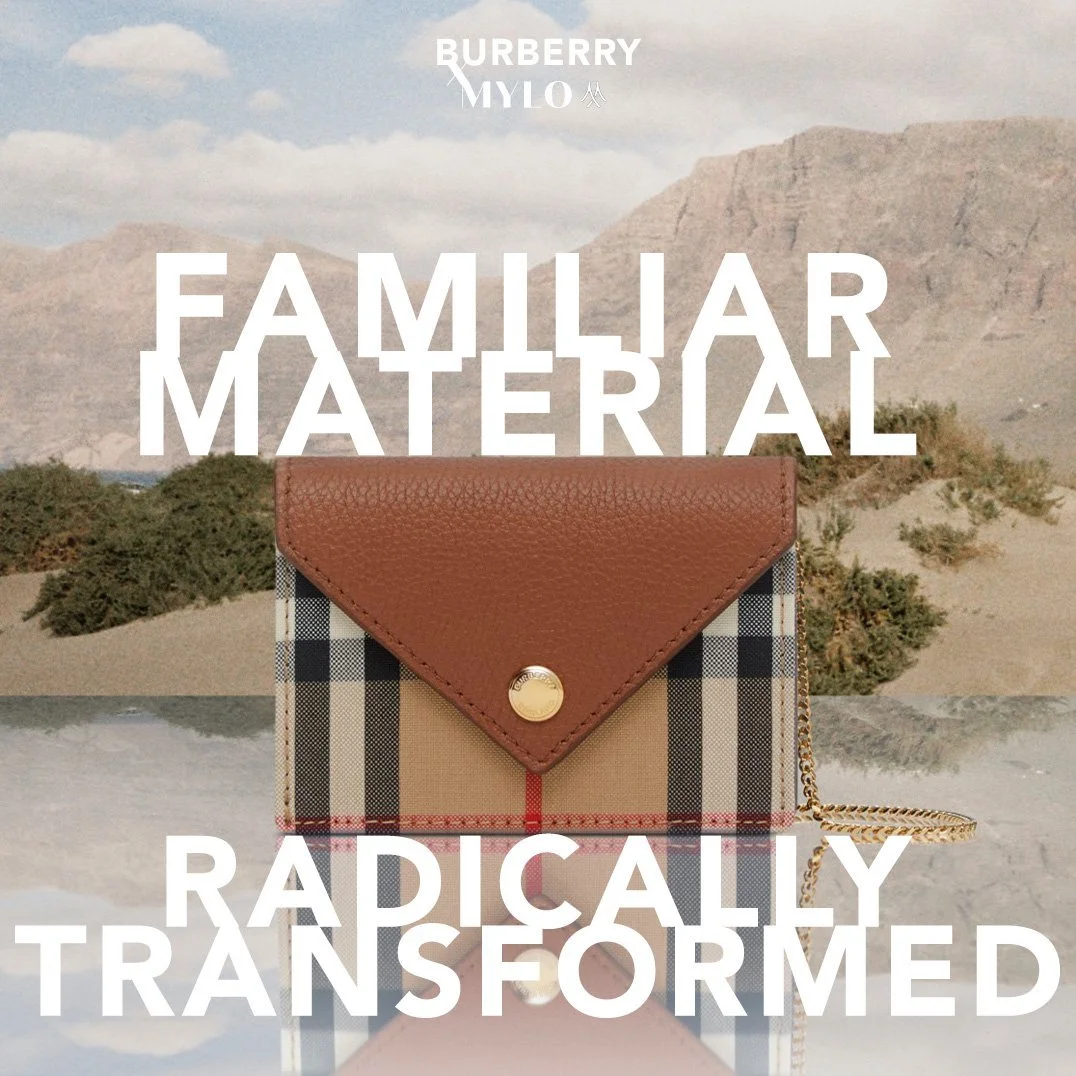 A Burberry wallet with a Burberry check pattern and brown leather flap, set against a desert landscape with mountains in the background. The text overlay says "Familiar Material" and "Radically Transformed".