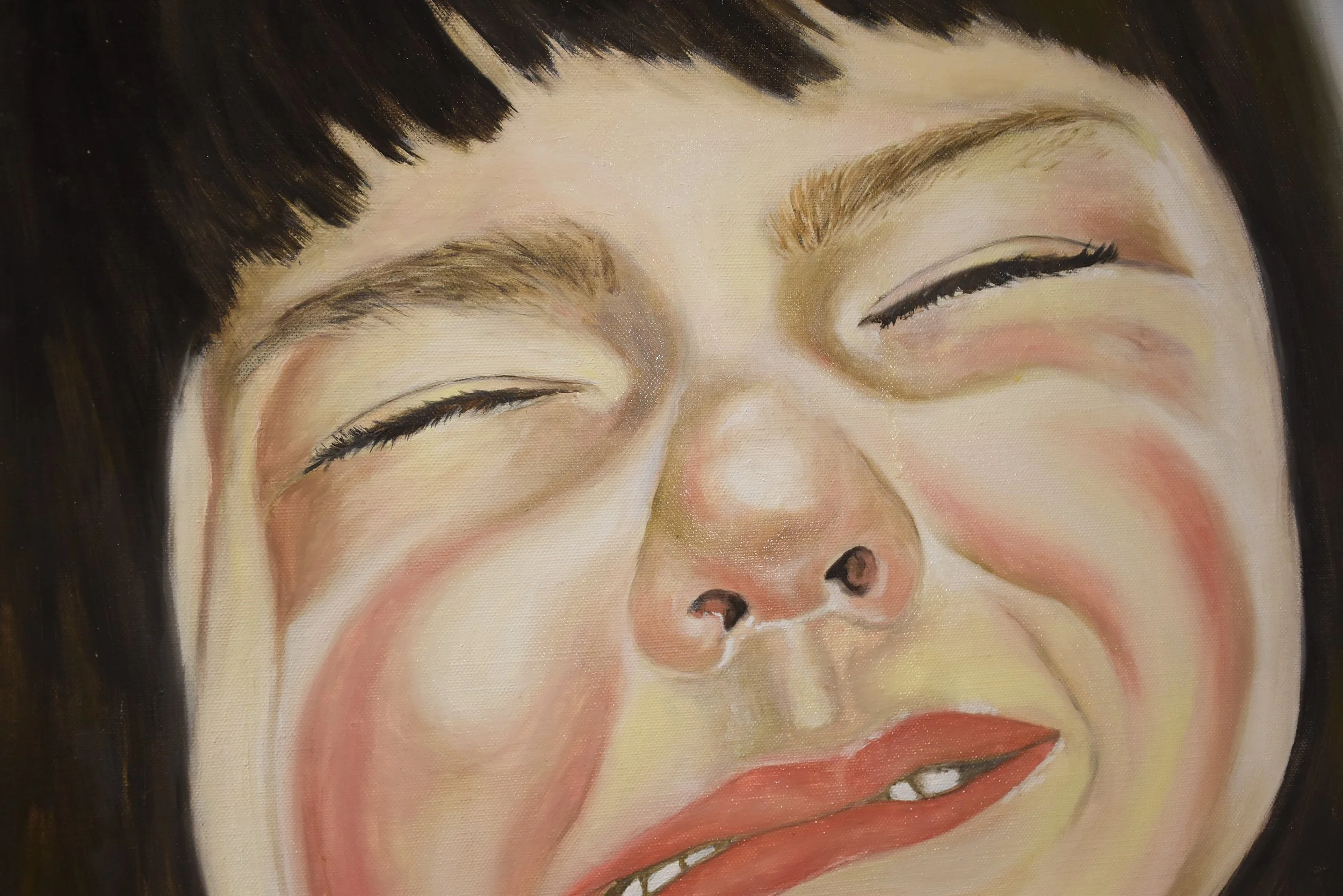 Close-up of a smiling woman with black hair, closed eyes, slightly open mouth showing teeth, and flushed cheeks.