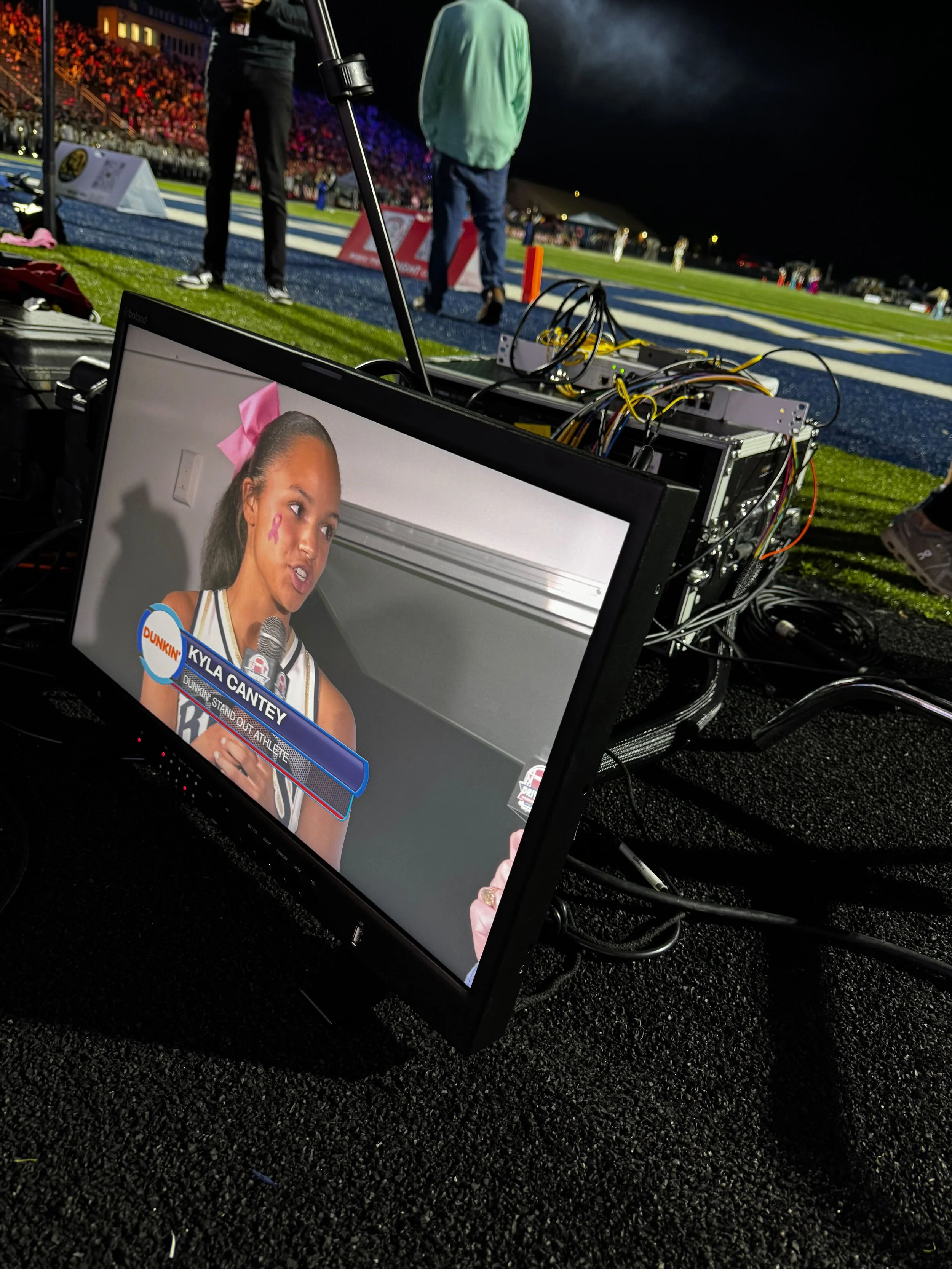 Dunkin branded broadcast desk with cheerleaders and crowd