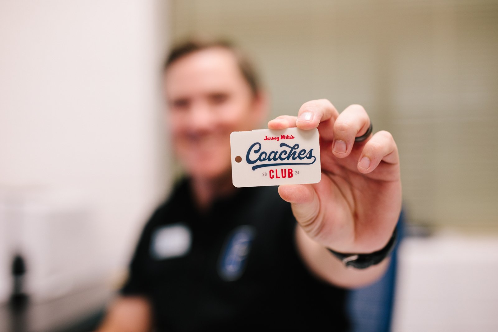 Person holding a Jersey Mike's Coaches Club card.