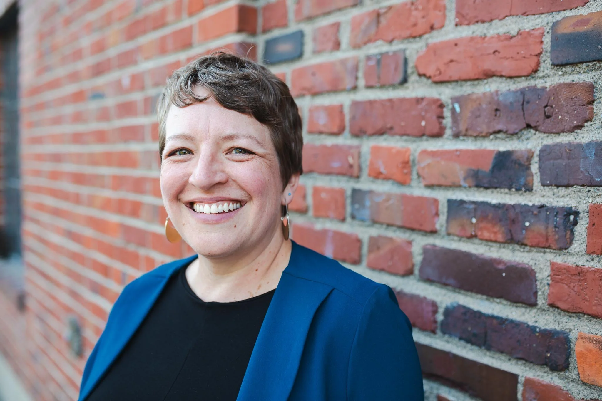 Seattle woman posing for headshots in front of brick building at Golden Gardens
