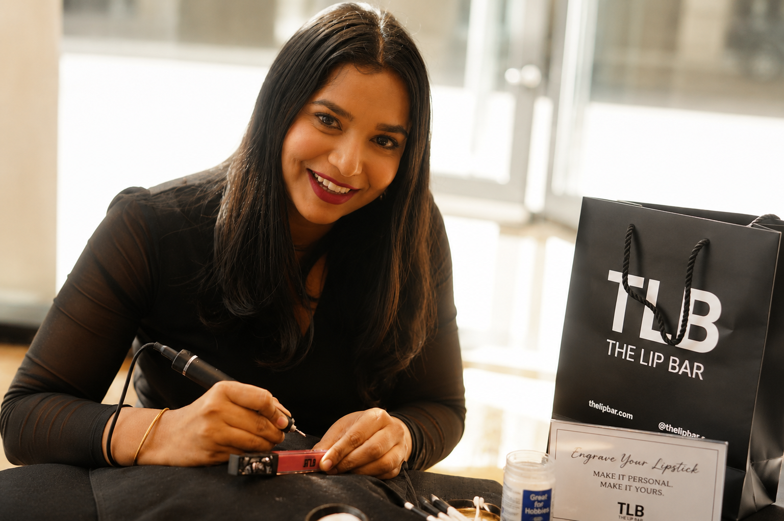 Artist providing live lipstick engraving at The Lip Bar Detroit during National Lipstick Day, creating personalized beauty products for guests at a retail brand activation.