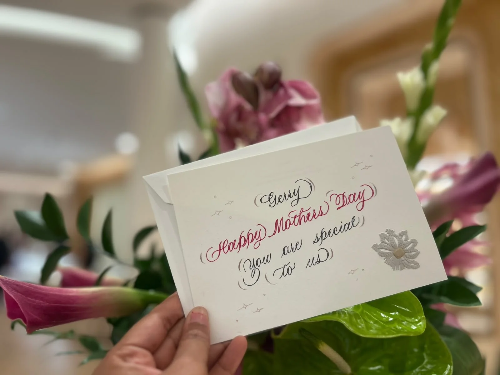 Live calligraphy artist personalizing a Mother's Day greeting card during a Cartier luxury retail brand activation and customer engagement event in Detroit.