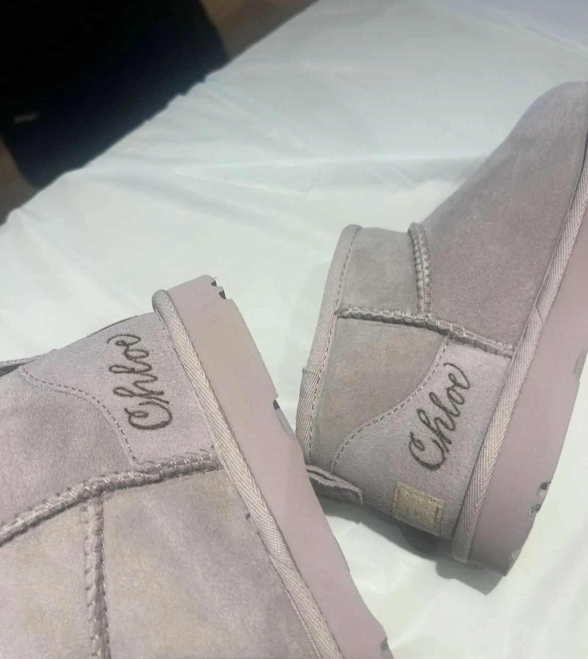 A pair of new light gray high-top sneakers with the brand name 'Choo' embroidered on the side, resting on a white surface.