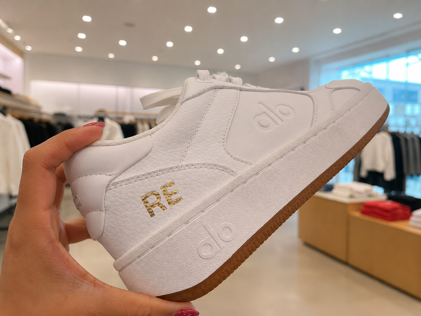ALO Yoga sneaker personalized with gold initials by a live personalization artist during a luxury retail brand activation. Custom shoe painting and sneaker personalization for experiential marketing events.