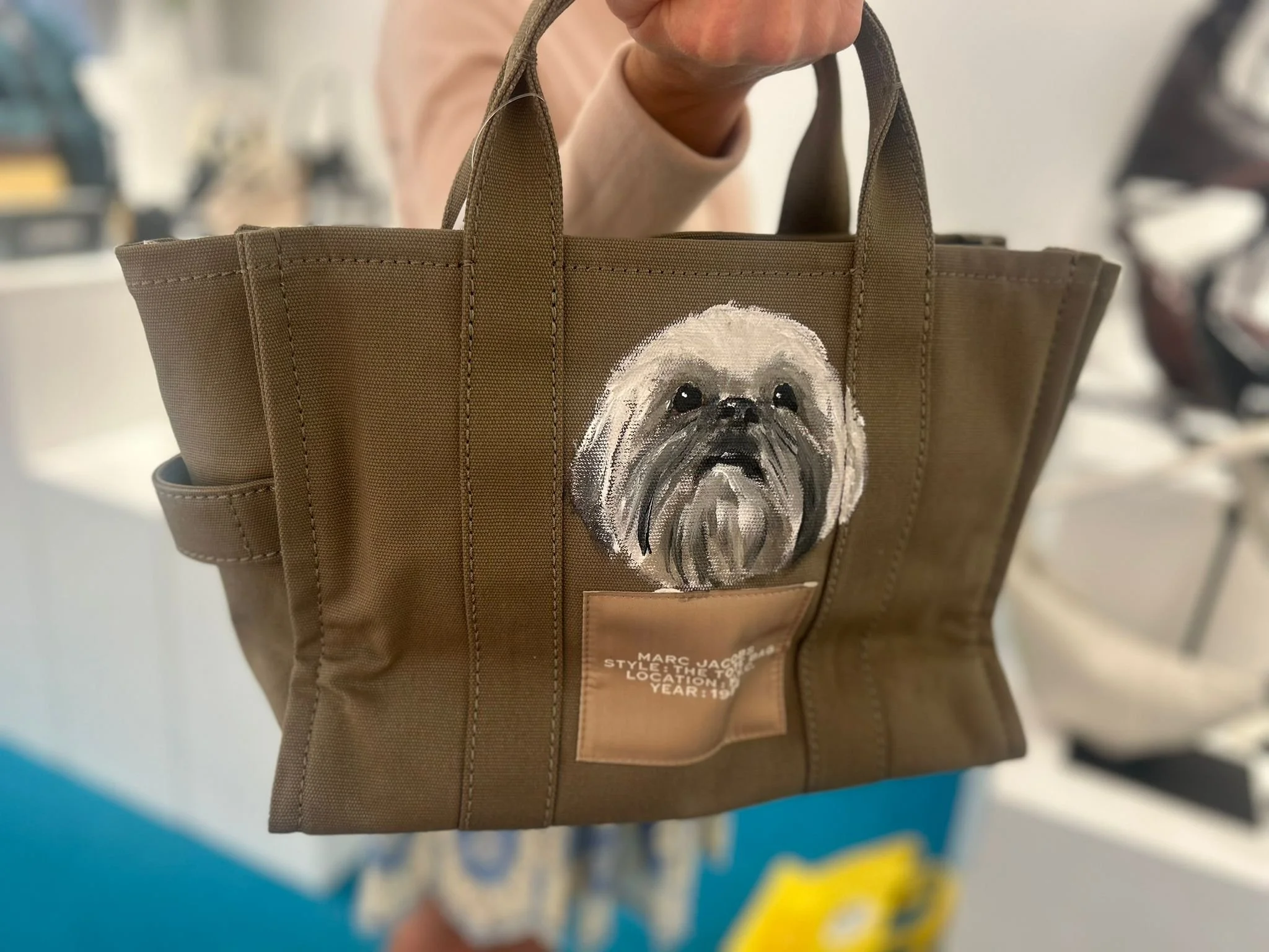 Brown tote bag with a painted image of a small dog, possibly a Shih Tzu, on the front.