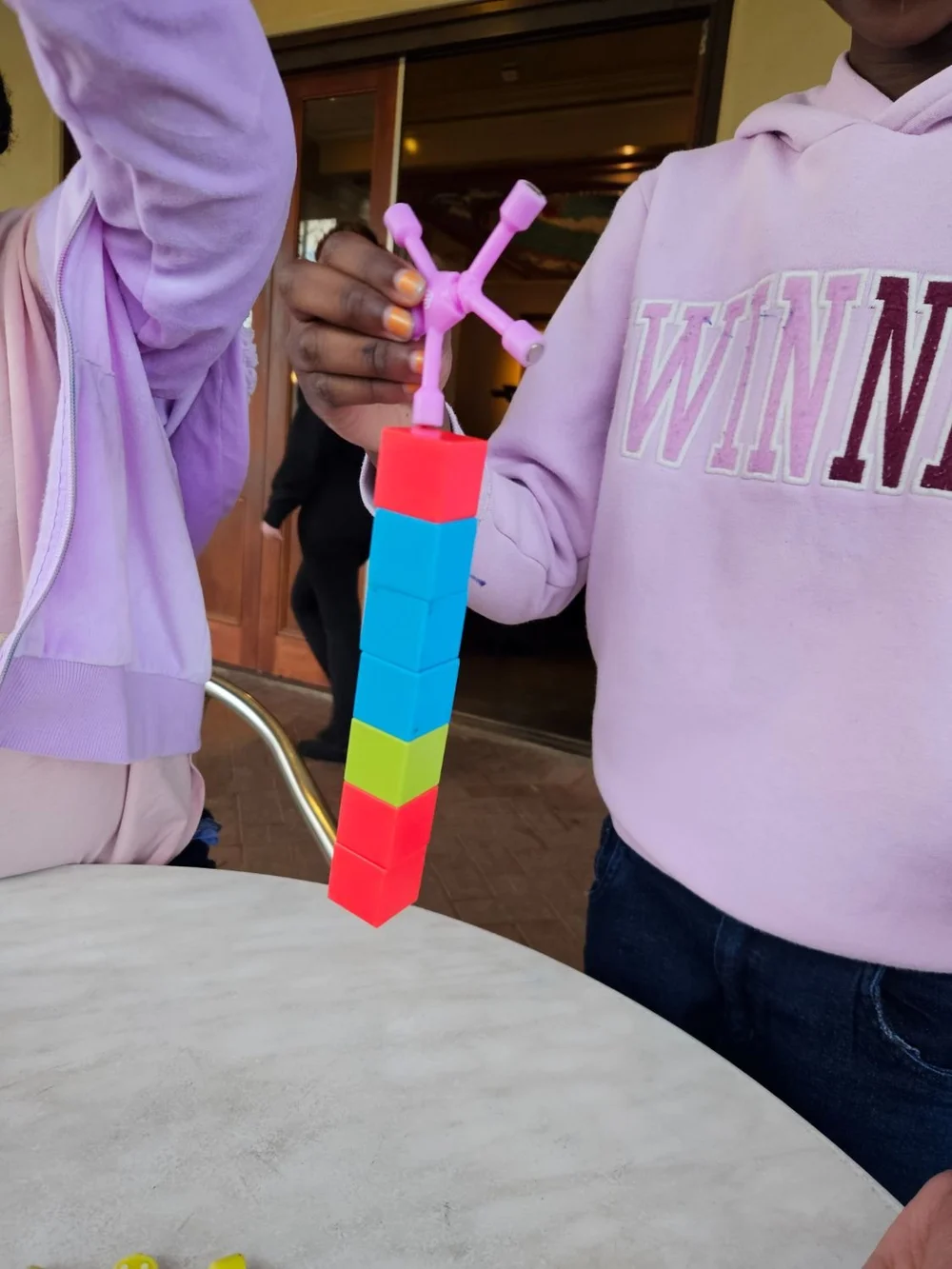 A child holding up a tall tower built from magnetic cubes