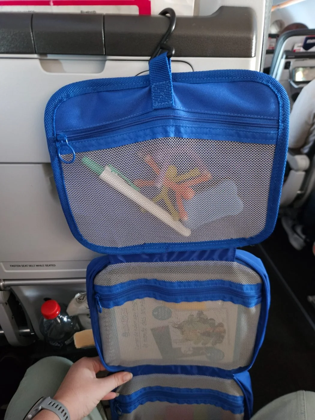 The kit hooked onto the back of an aeroplane seat, hanging open