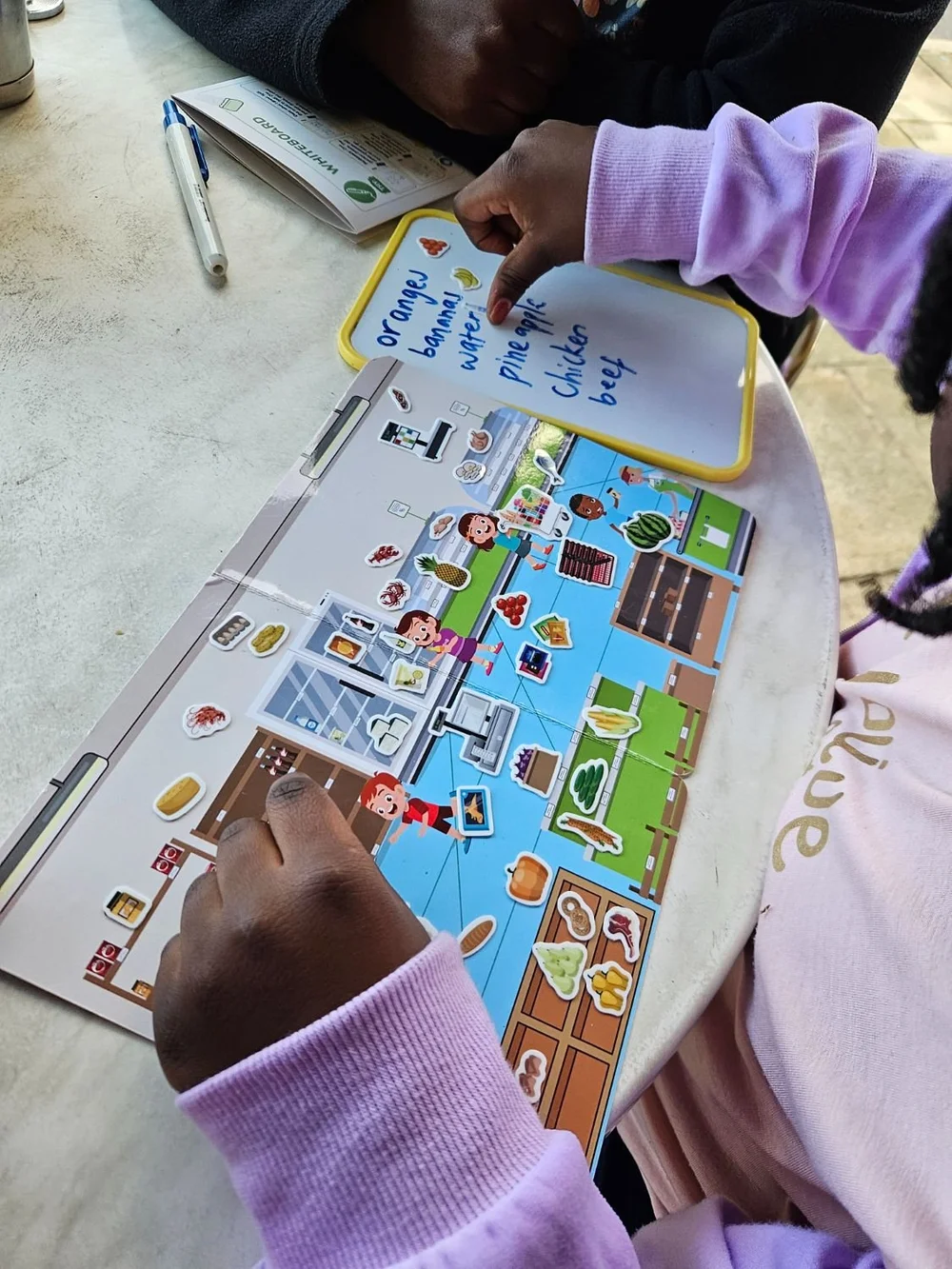 A child building a supermarket scene with reusable stickers