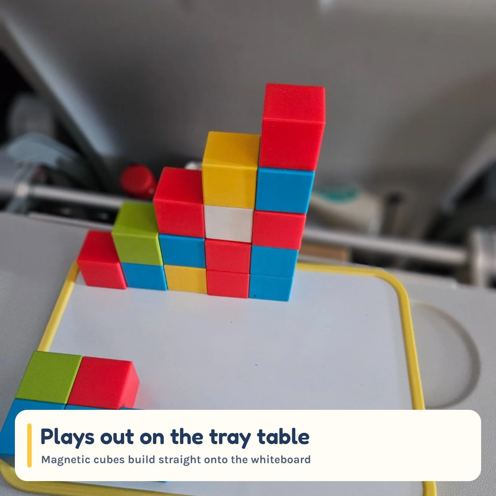 Magnetic cubes built into a tower on the whiteboard, on an open aeroplane tray table
