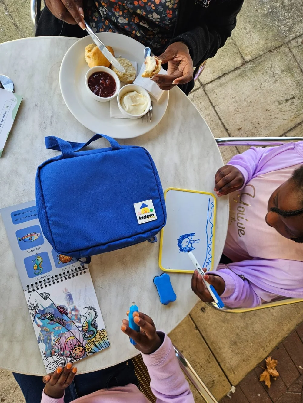 A child drawing on the double-sided whiteboard at a cafe table