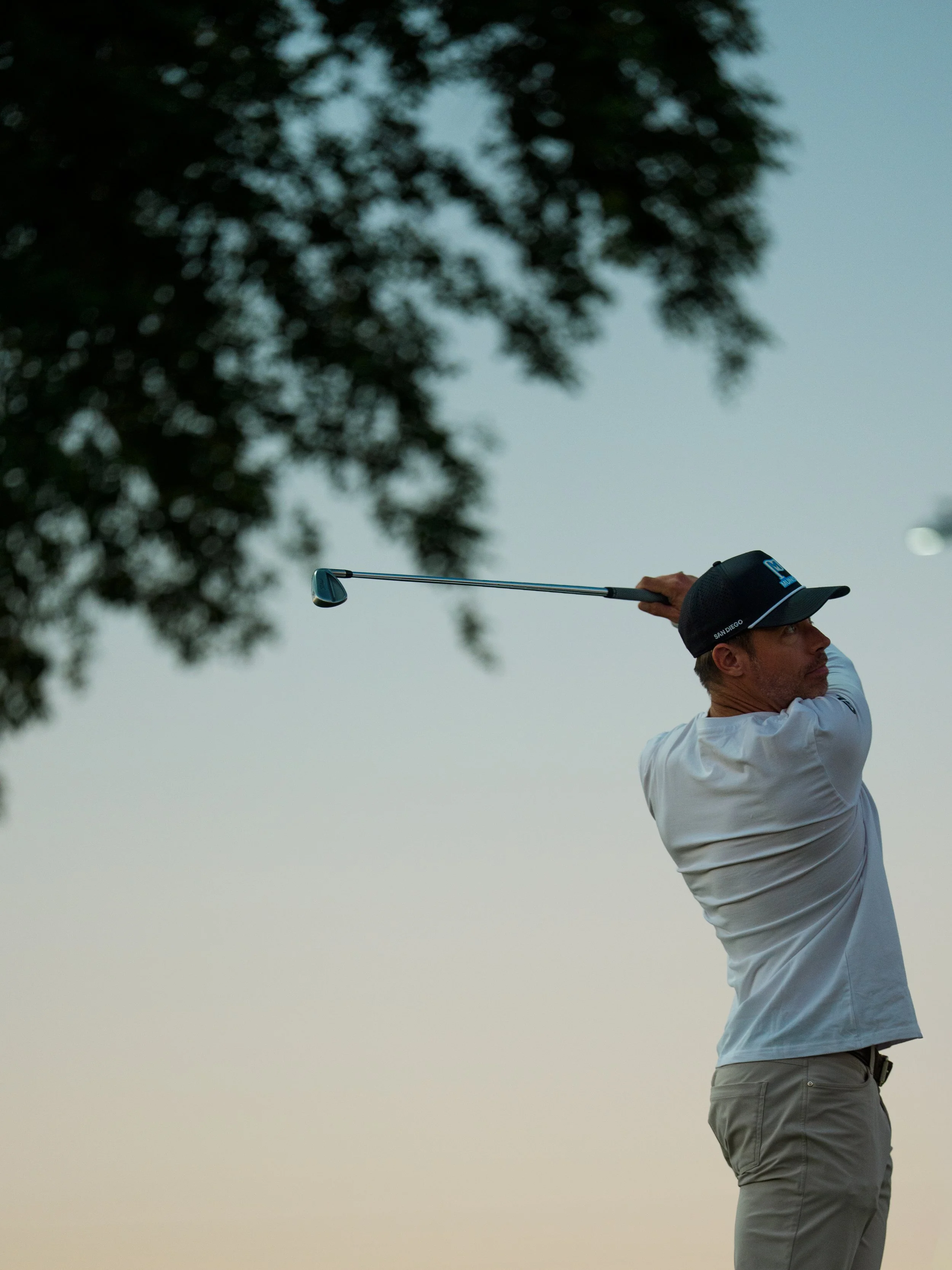 Player from the San Diego Munis tees off during sunset at the 2025 Grass League Championship in Tempe, Arizona.