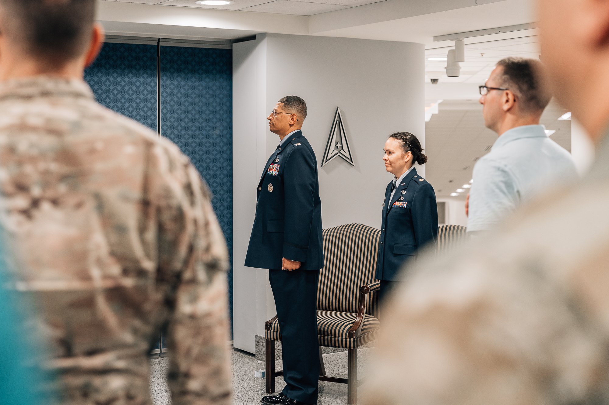 Military personnel standing during a ceremony, with two officers in dress uniforms in focus.