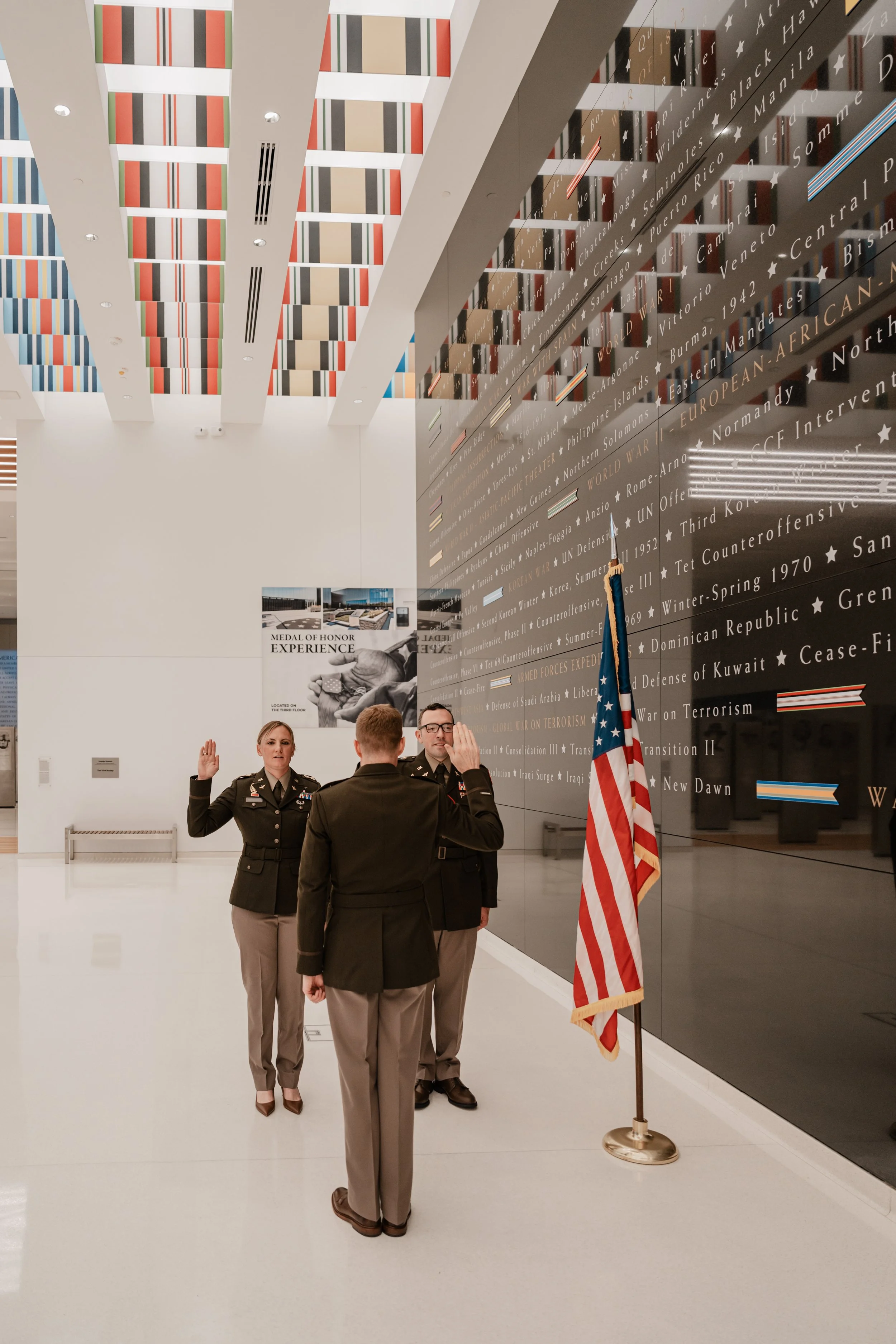 A military officer in uniform taking an oath at a ceremony in George Washington's Mount Vernon, with an American flag and an official behind a podium.