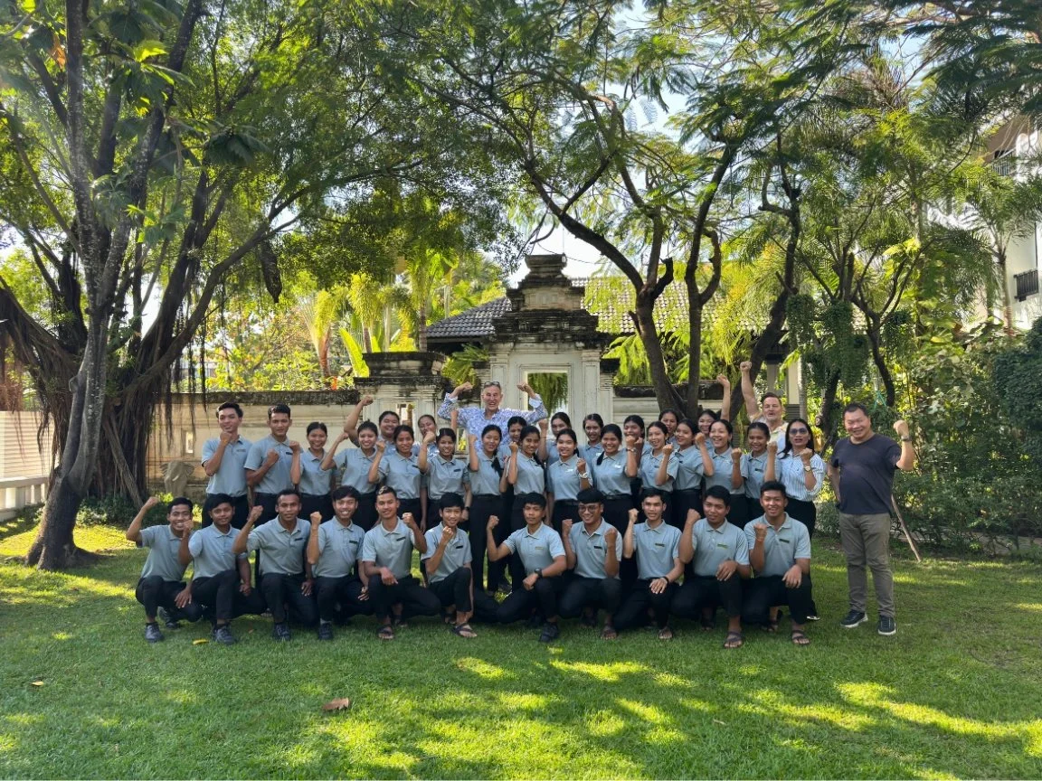 Shinta Mani Foundation hotel-designer-bill-bensley-and-shinta-mani-foundation-hospitality-students-pose-together-in-a-garden.jpeg