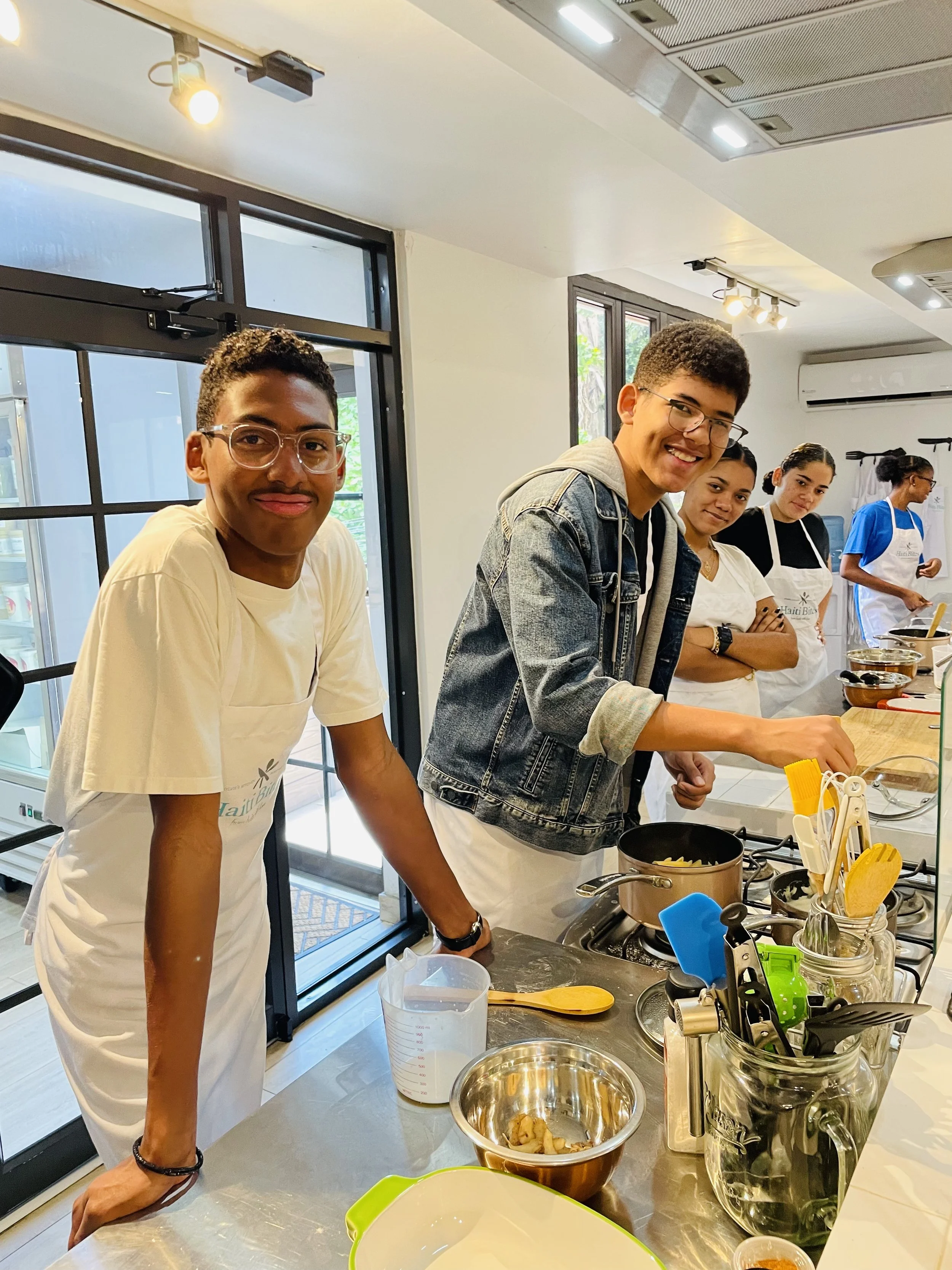 Group of people cooking in a kitchen, using utensils and cookware on a counter.