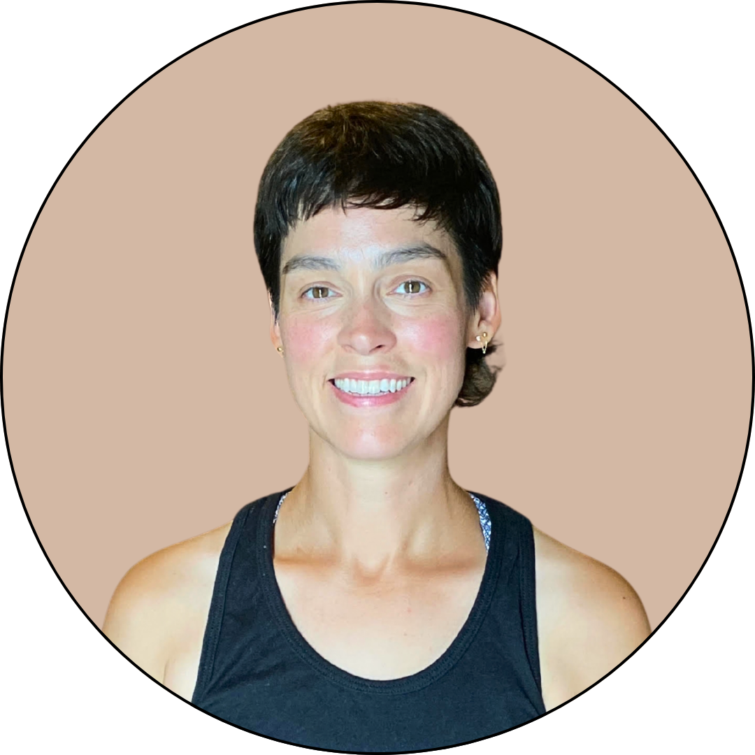 A woman with short dark hair, wearing a black tank top, smiling at the camera against a beige background.