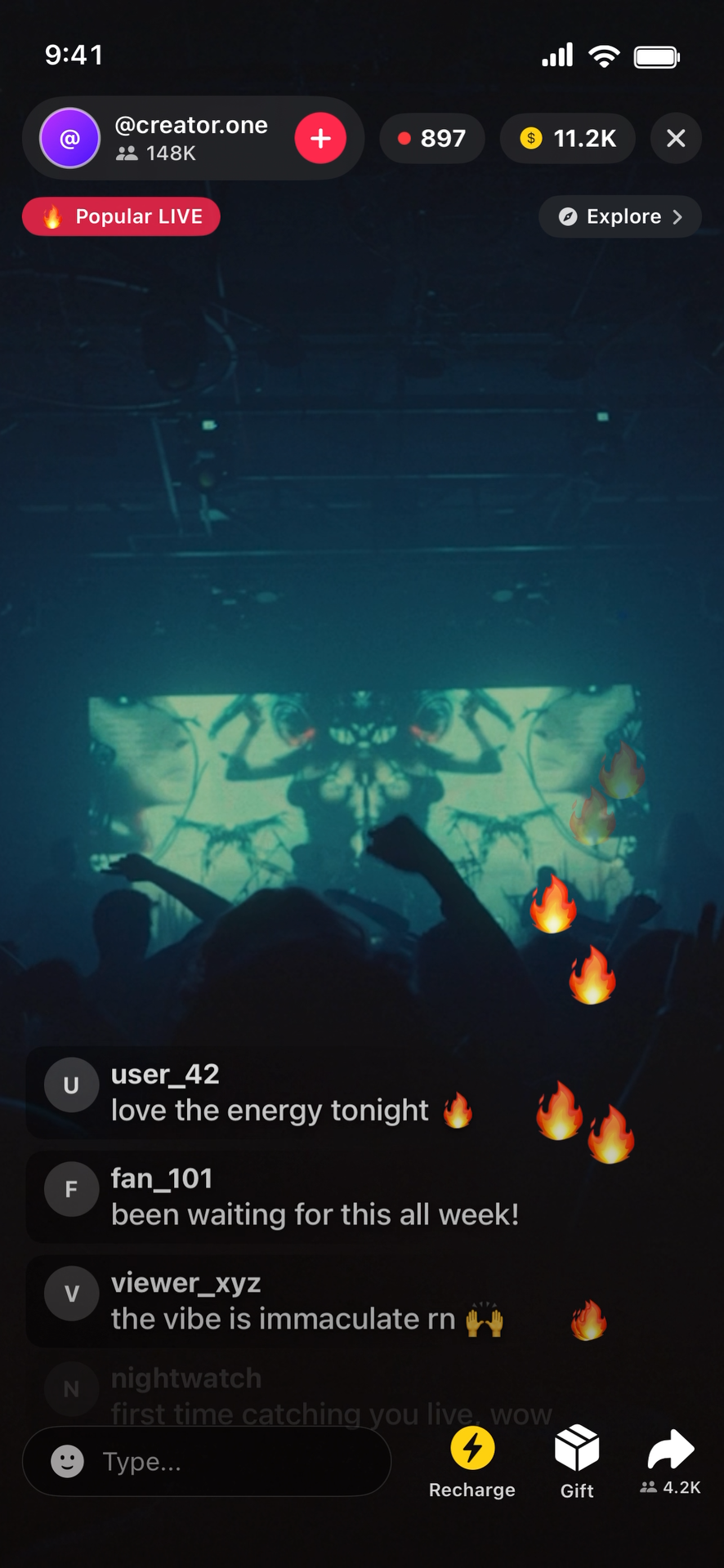 Dark concert venue with a large LED screen displaying symmetrical abstract visuals, audience silhouettes, graffiti style art, and many animated fire emojis across the screen and in chat comments. The top shows live viewer stats and chat comments praising the energy and vibe.