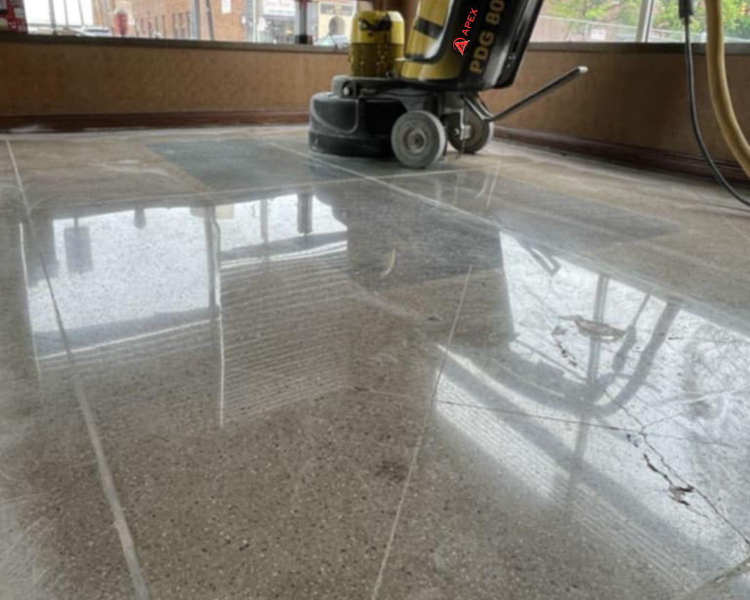 Floor polishing machine on a glossy tiled floor near a window.