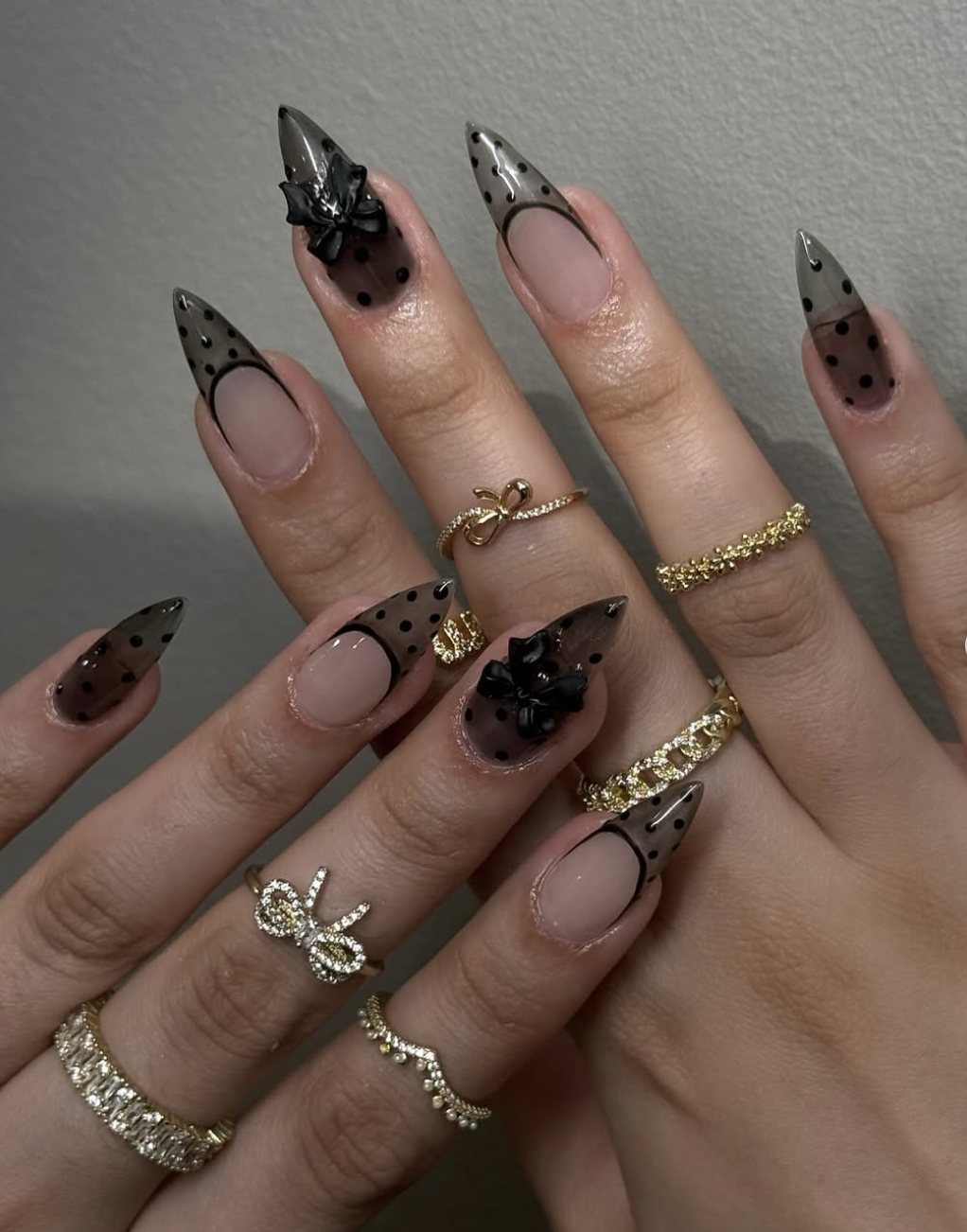 Long coffin-shaped nails with a black lace pattern on the tips over a sheer nude base.