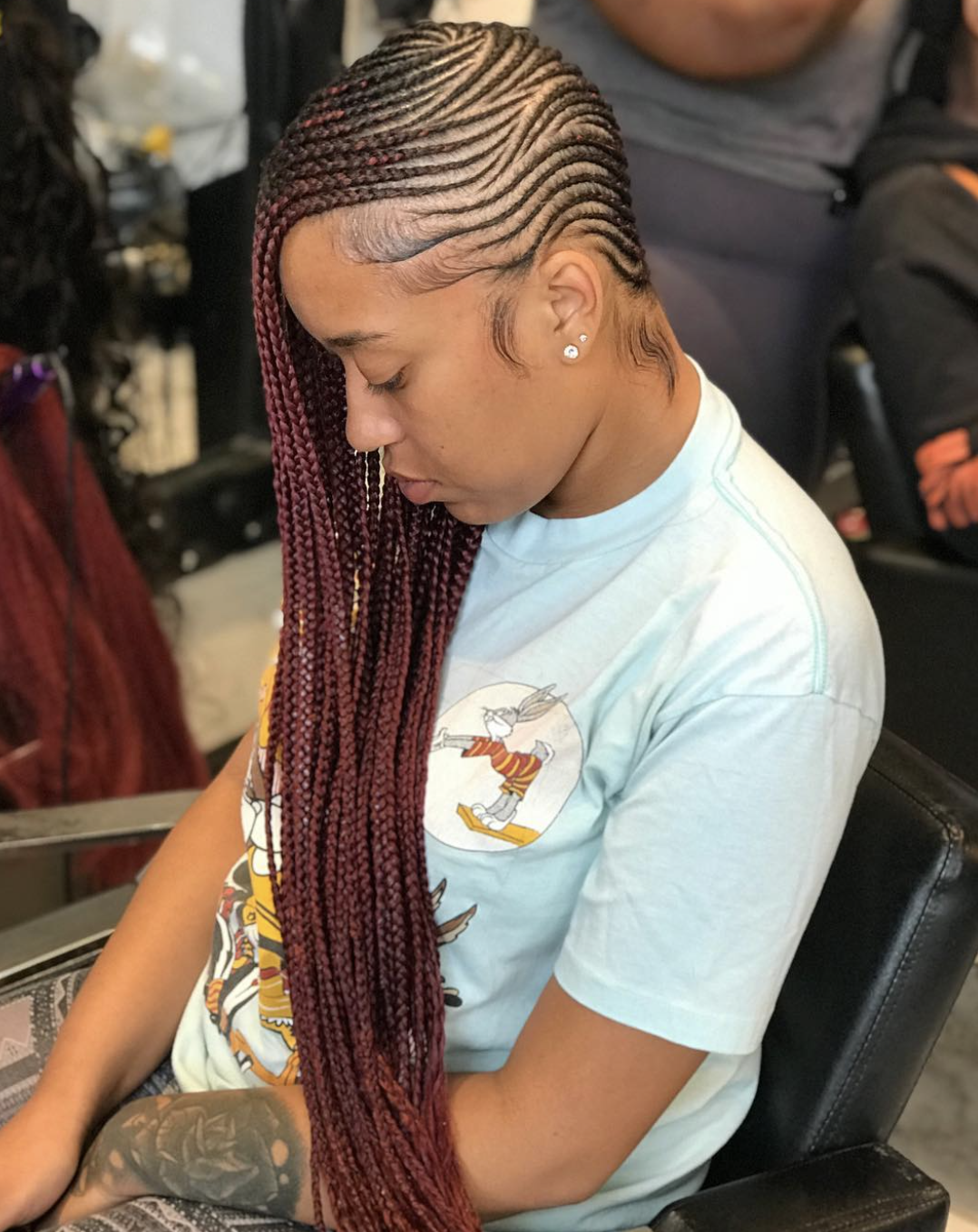 Long braids swept over one shoulder to create an asymmetrical hairstyle.