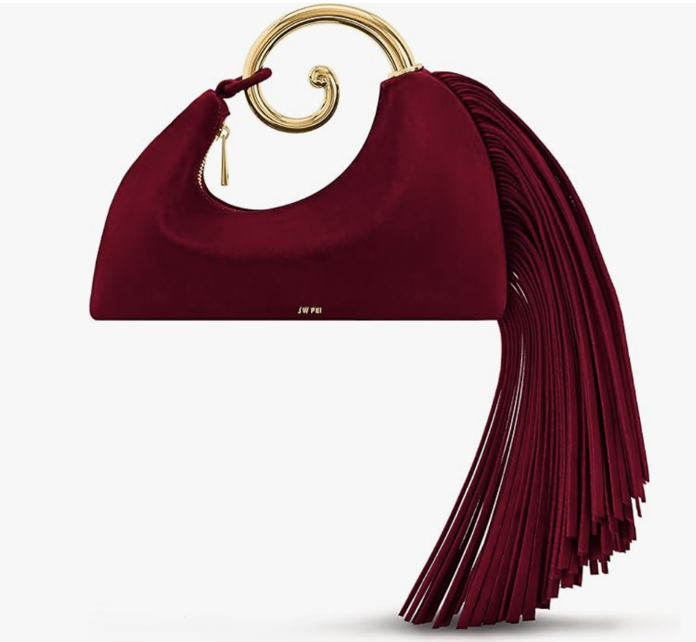A burgundy crescent-shaped handbag with a gold ring top handle and long, matching wine-colored fringe tassels hanging from the side.