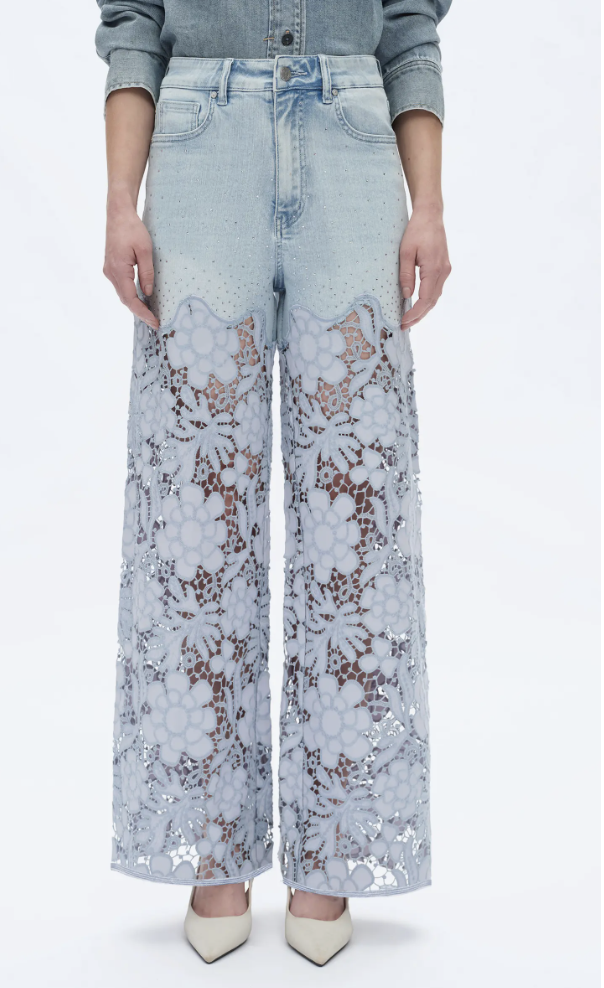A woman wearing light blue wide-leg jeans by Bayeas featuring an intricate floral lace overlay and subtle crystal embellishments, styled with cream pointed-toe heels.