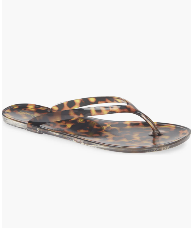 A close-up product view of a pair of glossy tortoise shell pattern thong-style jelly sandals on a white background.