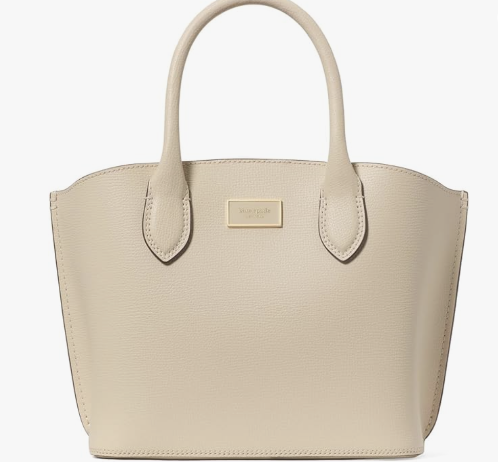 A structured beige Kate Spade crossgrain leather tote bag with slim shoulder handles and a gold logo plate, styled as a polished accessory for a spring capsule wardrobe for women in their 60s.