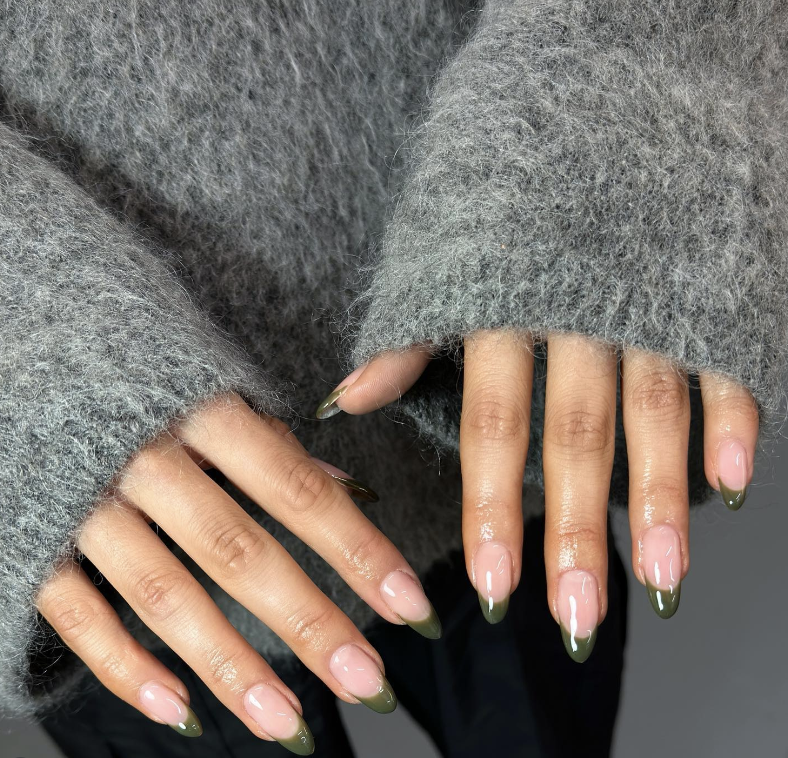 Sheer nude nails finished with muted olive green French tips.