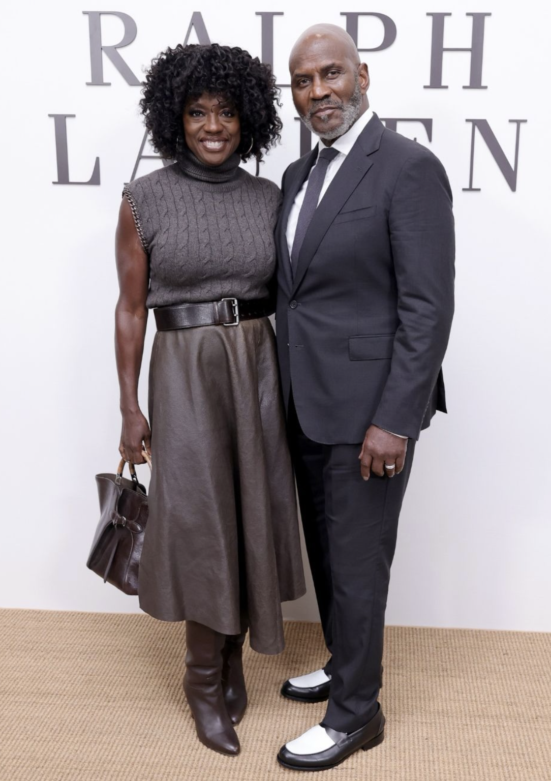 Viola Davis wearing a sleeveless charcoal cable-knit top, brown leather midi skirt, wide belt and tall brown boots at Ralph Lauren.