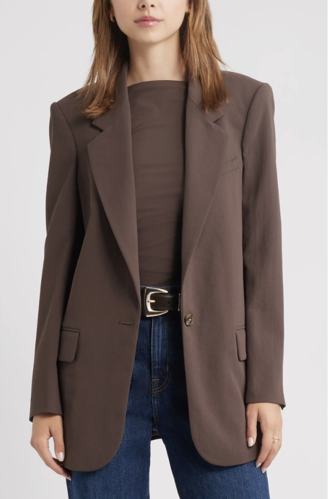 Woman wearing a brown blazer, chocolate brown top, dark wash jeans, and a statement belt.