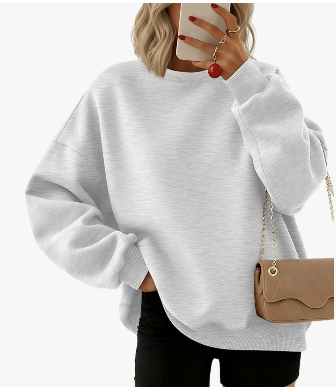 Front view of a woman wearing an oversized grey crewneck sweatshirt tucked into black leggings, accessorized with a small tan crossbody bag.
