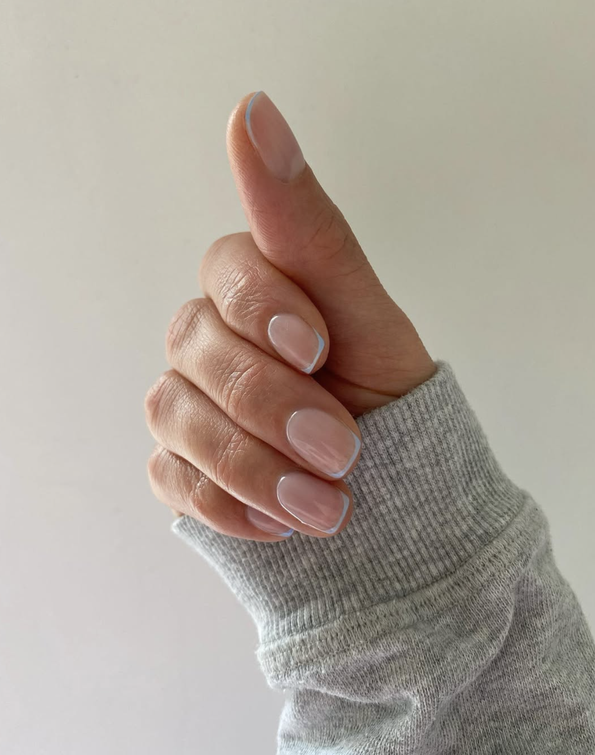 Short winter nails with icy blue micro French tips over a sheer base
