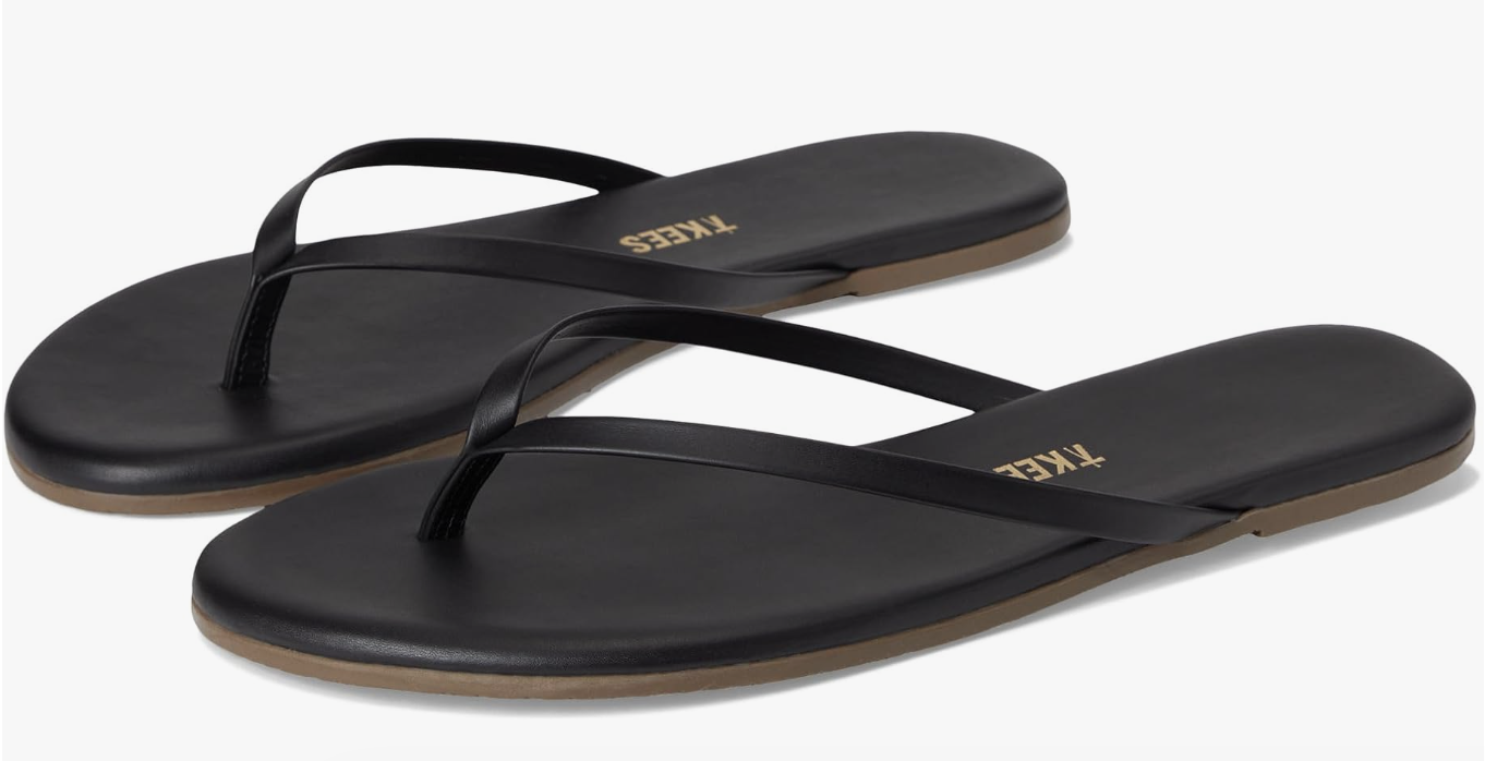 A pair of TKEES Linere matte black leather flip-flops with a minimalist thin strap design, displayed on a white background.