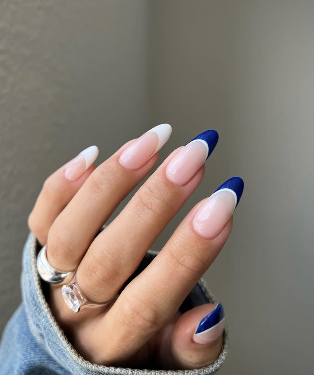 Long, oval-shaped nails showcasing a clean, natural base with striking cobalt blue French tips.