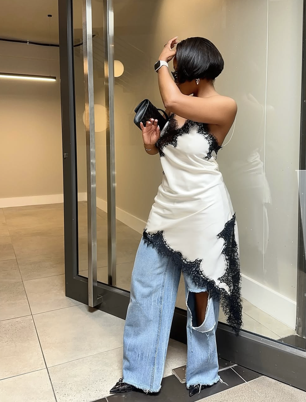Petite woman wearing black pointed-toe slingback micro-heels with distressed wide-leg jeans and a white lace-trim camisole.