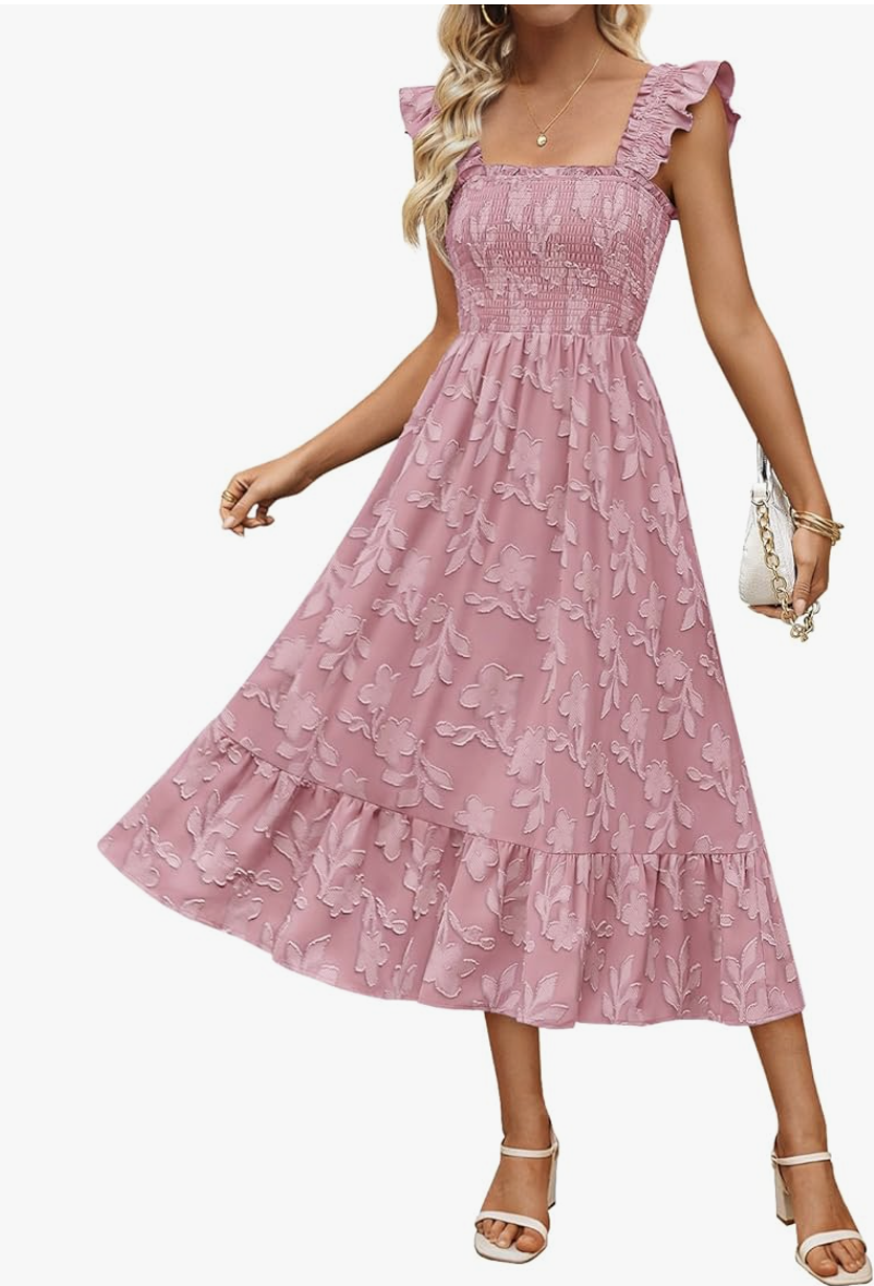 A woman wearing a pink floral midi dress with a smocked bodice, flutter sleeves, and a tiered ruffle skirt.