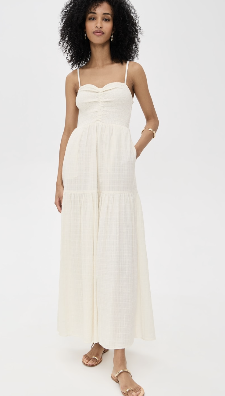 A woman wearing the white LSPACE Mallorca Dress, a sleeveless tiered maxi dress with a smocked bodice.
