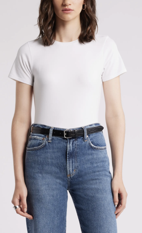Fitted white t-shirt tucked into blue jeans with a black belt.