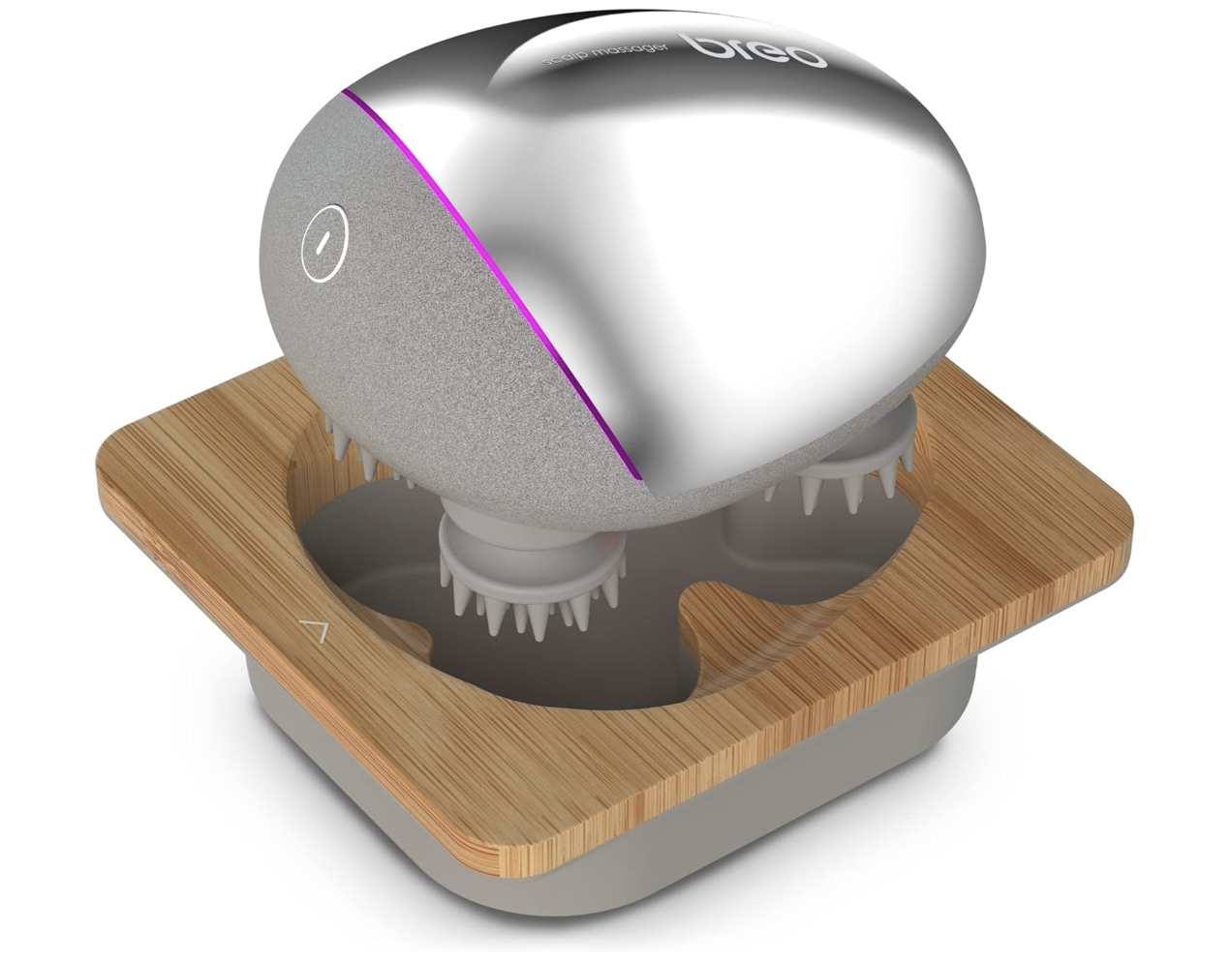 A silver Breo Scalp Mini Head Massager with a bamboo charging base, showing the soft kneading nodes designed for tension relief and dry scalp massage during protective style season.
