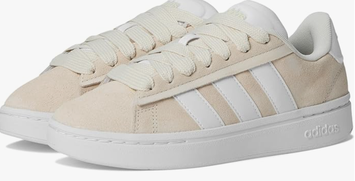 A pair of white adidas Women's Grand Court Alpha 00s Sneakers with signature cream stripes, shown as a polished footwear option for a comfortable professional office wardrobe.