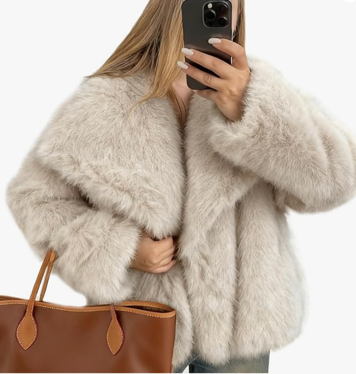 A product shot of a voluminous white faux fur coat with a lapel collar, styled with a brown leather tote bag. This piece illustrates the "Style Math" for layering a light base under high-texture outerwear.