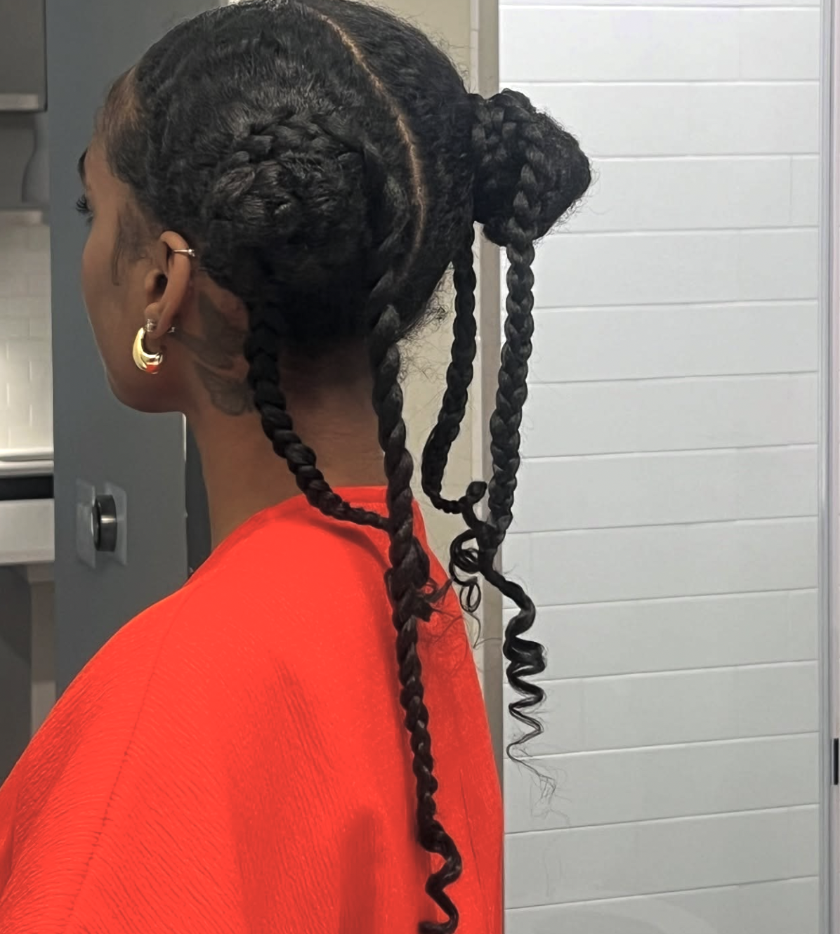 Long braids styled into two high space buns with slim face-framing pieces.