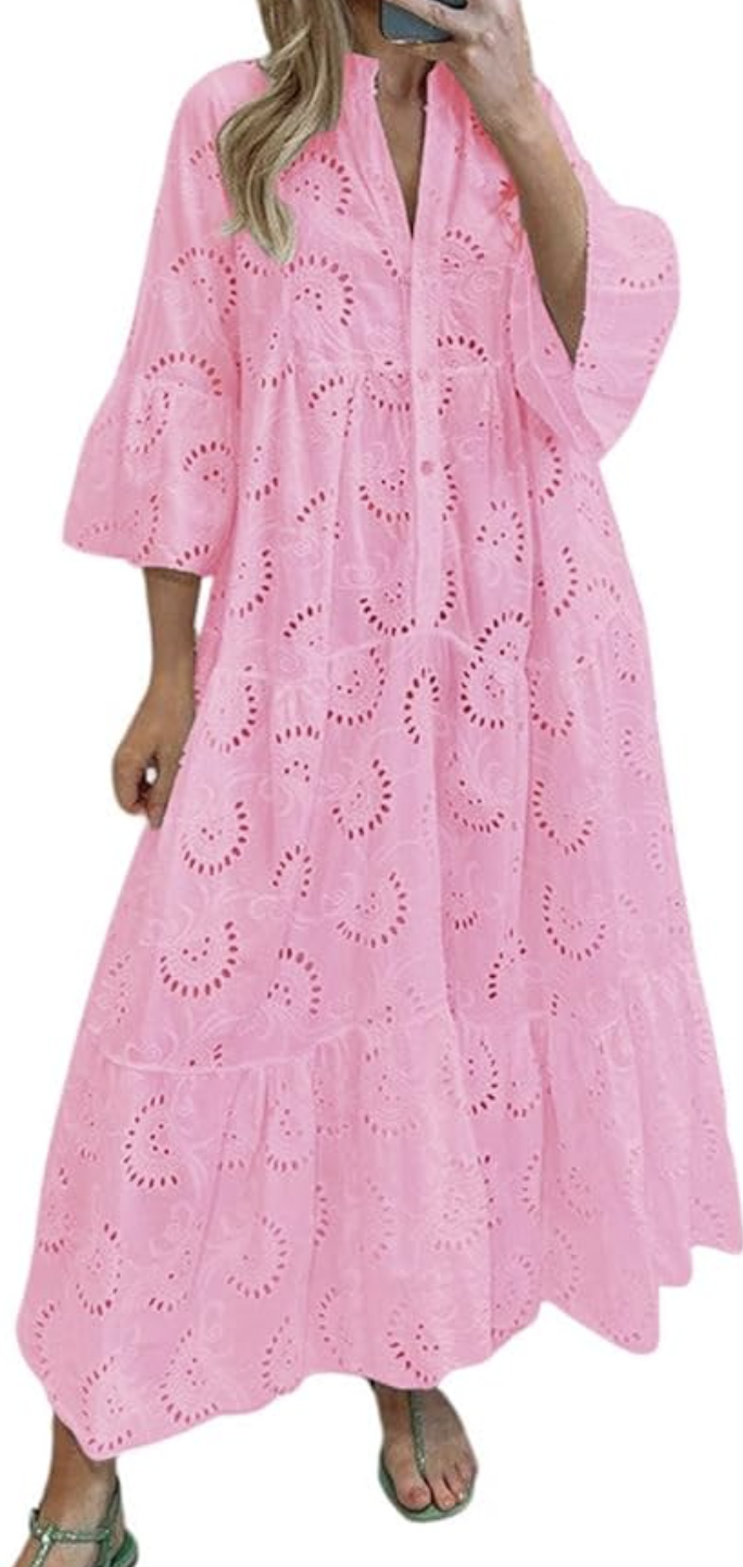 A woman wearing a bright pink eyelet lace midi dress with short flutter sleeves and a tiered skirt, a comfortable and stylish spring dress option for women in their 60s.