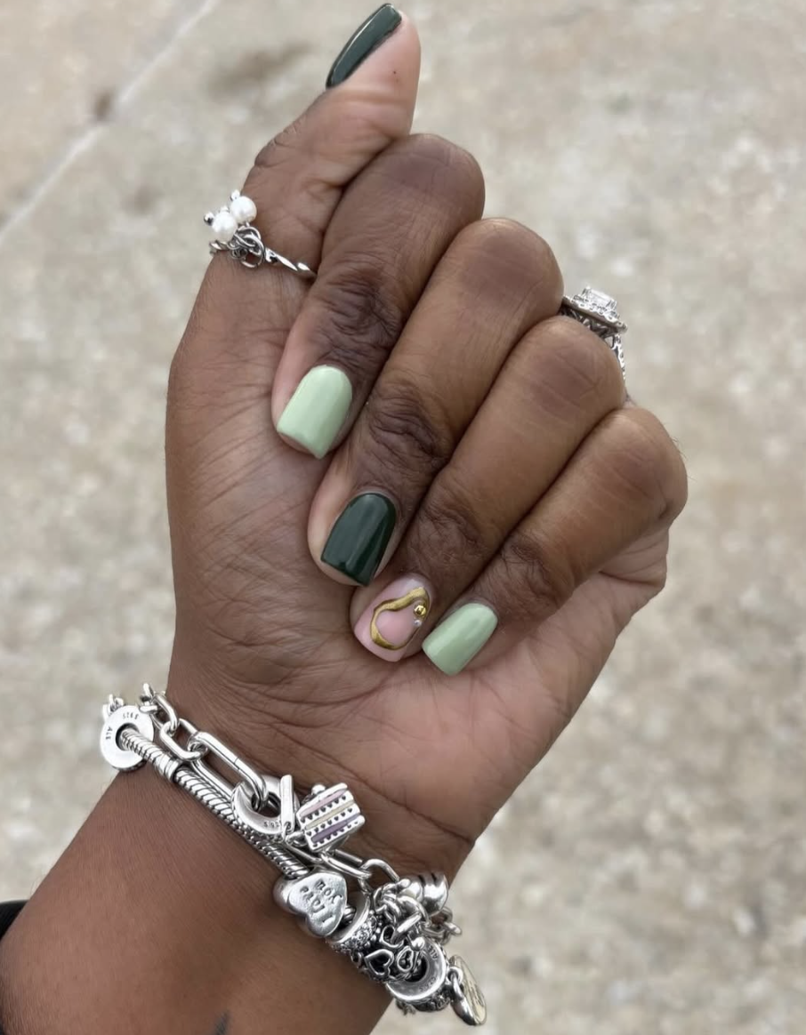 A close-up of short nails featuring a mix of deep forest green and light mint green solid polish.