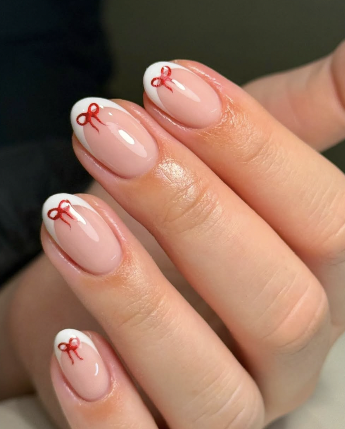 Sheer pink Christmas nails with red French tips and white bows