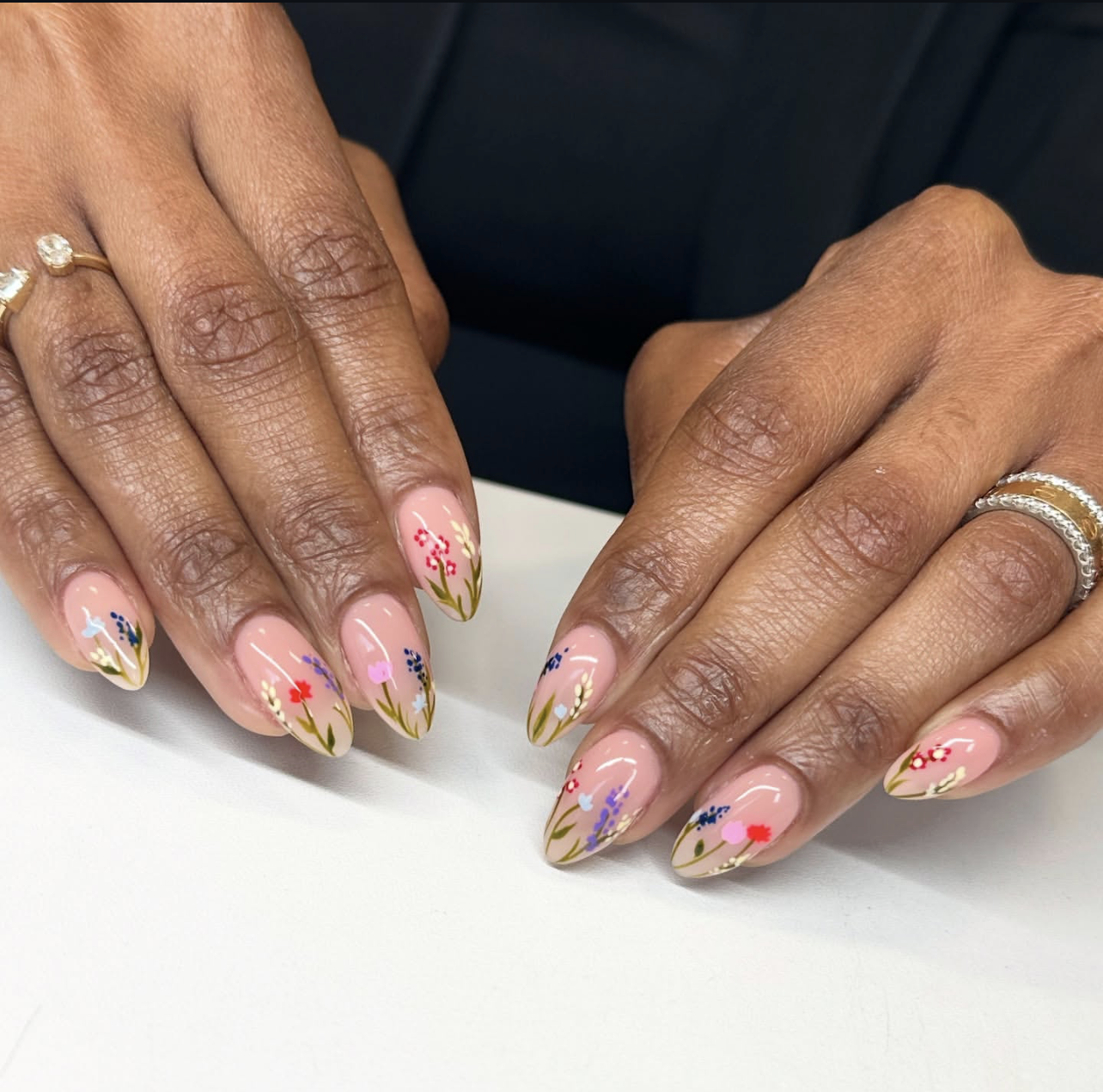 Long oval nude nails with intricate hand-painted wildflowers in red, purple, and yellow.