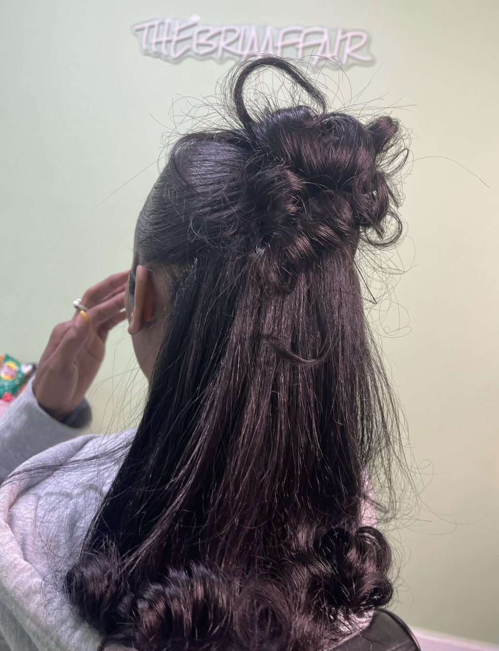 Silk press hair styled half-up into a high, voluminous ponytail