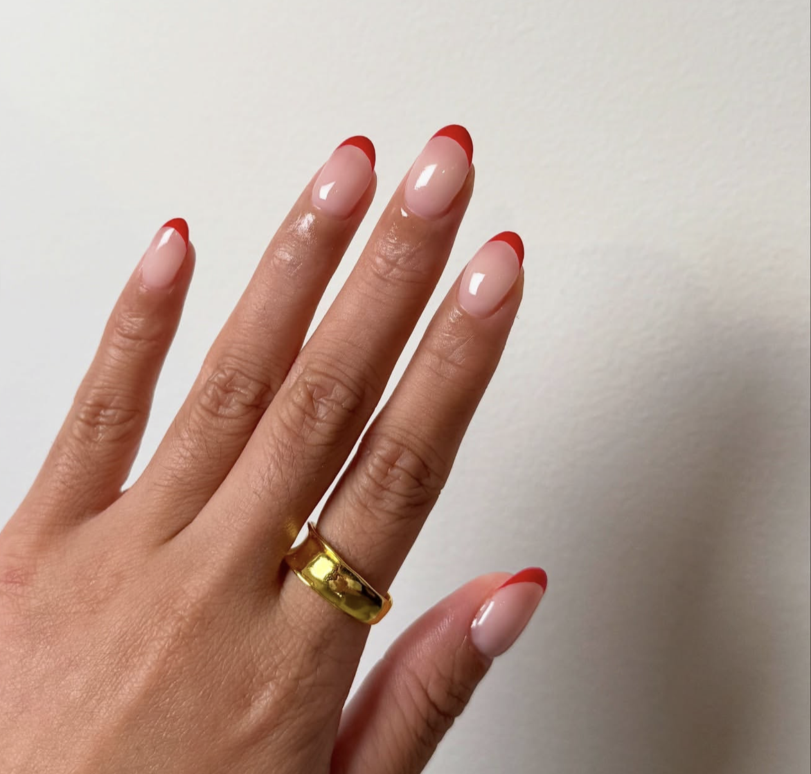 Long, oval-shaped nails with a glossy, semi-sheer milky white base coat and precise, thin cherry red French tips.